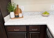 Thumbnail 1 of 12 - A kitchen with dark brown cabinets and a marble countertop.