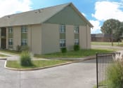 Thumbnail 1 of 8 - an apartment building with a fence and grass in front of it