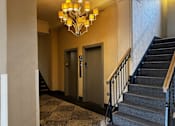 Thumbnail 6 of 43 - A staircase with a black metal railing and a chandelier hanging from the ceiling.