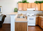 Thumbnail 14 of 14 - A kitchen with wooden cabinets and a white stove top oven.
