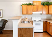 Thumbnail 11 of 14 - A kitchen with wooden cabinets and a white stove.