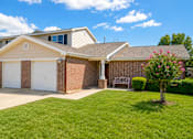Thumbnail 2 of 14 - A house with a white garage door and a brick wall.
