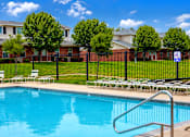 Thumbnail 12 of 14 - A swimming pool surrounded by a black fence and lawn chairs.