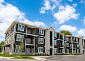 Thumbnail 1 of 9 - A large, modern apartment building with multiple balconies and doors.