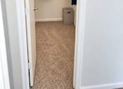 Thumbnail 33 of 37 - A white closet with clothes hanging up and a trash can.