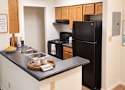 Thumbnail 28 of 37 - A kitchen with a black fridge and white cabinets.