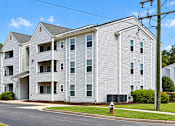 Thumbnail 20 of 37 - A large white apartment building with a tree in front of it.