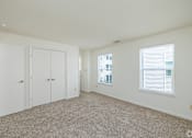 Thumbnail 11 of 20 - A room with white walls and carpeted floor with three white doors.