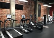 Thumbnail 17 of 34 - a group of exercise equipment in a gym with a brick wall