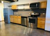 Thumbnail 23 of 34 - an empty kitchen with stainless steel appliances and wooden cabinets