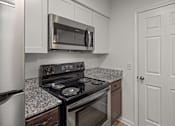 Thumbnail 5 of 14 - A kitchen with a stove, microwave, and refrigerator.at Mammoth at the Orchard Apartments, Rogers  