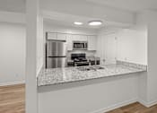 Thumbnail 7 of 14 - A kitchen with a granite countertop and stainless steel appliances.at Mammoth at the Orchard Apartments, Arkansas, 72756