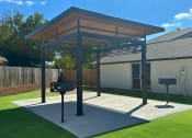 Thumbnail 12 of 14 - a pergola with two barbecue pits in a backyard at Mammoth at the Orchard Apartments, Rogers  