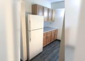 Thumbnail 7 of 10 - an empty kitchen with a white refrigerator and wooden cabinets