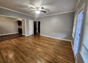 Thumbnail 8 of 13 - A room with a ceiling fan and wooden flooring.