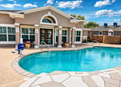 Thumbnail 6 of 9 - A swimming pool in front of a house with a blue sky in the background.