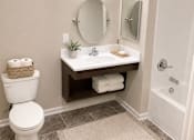 Thumbnail 13 of 15 - A bathroom with a toilet, sink, mirror and rug.