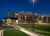 Thumbnail 7 of 15 - A streetlight stands in front of apartment buildings at dusk.