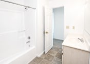 Thumbnail 9 of 9 - A white bathroom with a tub, sink and toilet.