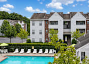 Thumbnail 7 of 9 - A pool in front of a white and brick building with a yellow umbrella.