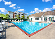 Thumbnail 3 of 9 - A large swimming pool with a red border and white lounge chairs.
