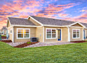 Thumbnail 29 of 32 - A house with a brown roof and tan siding is shown with a blue sky in the background.