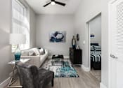Thumbnail 15 of 17 - A living room with a grey armchair and a white sofa.