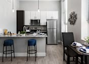 Thumbnail 17 of 17 - A modern kitchen with a granite countertop and stools.