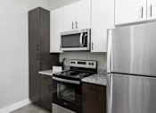 Thumbnail 16 of 17 - A modern kitchen with a stainless steel refrigerator, microwave, and oven.