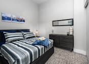 Thumbnail 14 of 17 - A bedroom with a bed, nightstand, and a painting on the wall.
