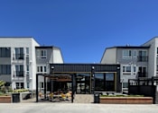Thumbnail 7 of 8 - A modern building with a black and white exterior and a covered outdoor seating area.