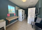 Thumbnail 6 of 18 - a laundry room with washer and dryer and a table with a washing machine