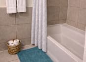 Thumbnail 4 of 5 - A white shower curtain hangs over a white bathtub in a bathroom.
