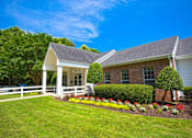 Thumbnail 14 of 20 - A house with a white fence and a garden in front.