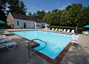 Thumbnail 20 of 20 - A pool with a red brick border and white chairs around it.