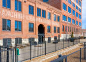 Thumbnail 31 of 34 - a large brick building with a fence in front of it