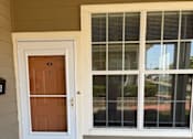Thumbnail 12 of 26 - A brown door is on the left and a window with blinds is on the right.