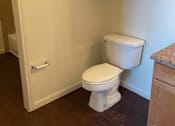 Thumbnail 17 of 26 - A white toilet in a small room with wooden cabinets.