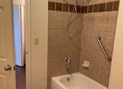Thumbnail 20 of 26 - A white bathtub with a shower head and a shower curtain rod.