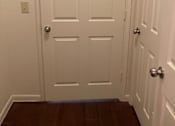 Thumbnail 23 of 26 - A white door with a silver handle is in the middle of a hallway.