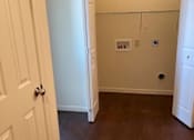 Thumbnail 25 of 26 - A white door is open to a room with a brown floor.
