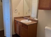 Thumbnail 8 of 26 - A bathroom with a white toilet, sink, and wooden cabinets.