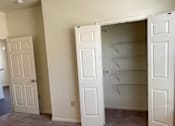 Thumbnail 7 of 26 - A room with two white doors, one open, and a ceiling fan.