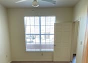Thumbnail 19 of 26 - A room with a carpeted floor and a window with blinds.