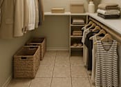 Thumbnail 26 of 47 - A small, well-organized, and tidy walk-in closet with a white counter and a framed picture on the wall.
