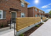 Thumbnail 14 of 14 - A sunny day at a brick apartment complex with a wooden fence.