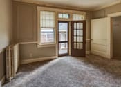 Thumbnail 11 of 15 - A room with a window, a door, and a carpeted floor.