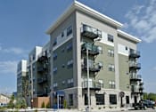 Thumbnail 4 of 7 - A large apartment building with a green and beige exterior.