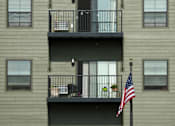 Thumbnail 6 of 7 - A building with a balcony and an American flag on a pole.