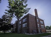 Thumbnail 99 of 100 - A large red brick building with a tree in front of it.